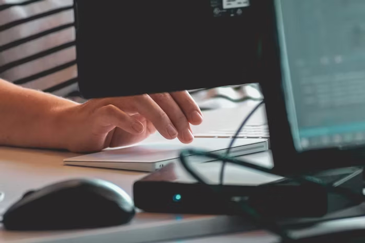 A person uses a computer at a work desk. 