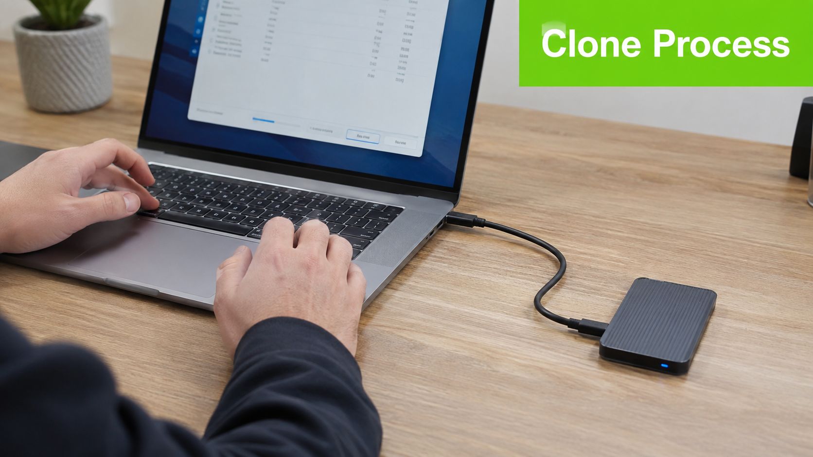 A person using a laptop connected to an external hard drive to initiate a drive cloning process.